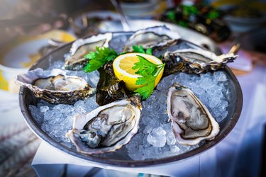 Half dozen fresh oysters are served with lemon in bowl with plenty of ice.