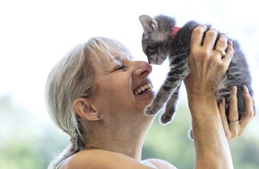 Mature woman holding kitten up, rubbing noses