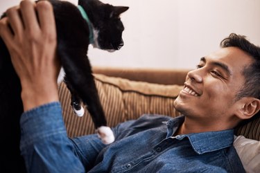 Shot of a young man playing with his cat