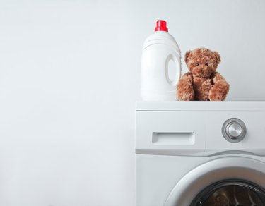 Bottle of liquid washing gel, teddy bear on a washing machine against a white background