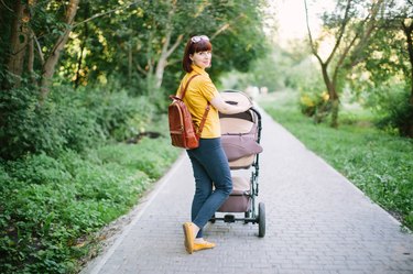 Woman walking in a park with a stroller.