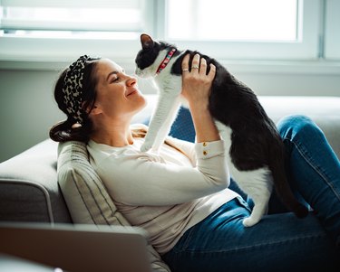 Woman sitting on a sofa and cuddling her cat