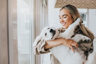 Young woman cuddles her 12 week old Golden Retriever Puppy