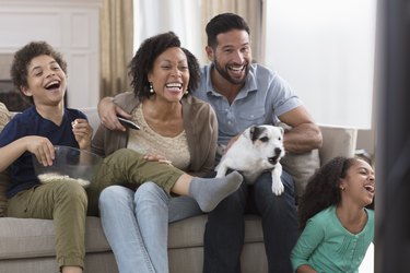 family having fun and watching tv with a barking dog on man's lap