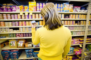 Woman shopping in supermarket looking at pet food