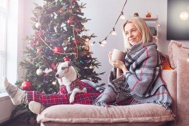 Woman with cup sit couch in house indoors with christmas x-mas atmosphere