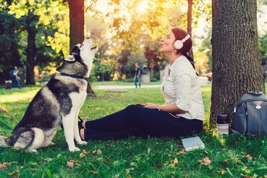 Woman with dog singing to the music in the park