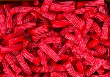 Heap of red strawberry licorice twizzlers red vine candies at supermarket. Creative sweet food confectionery pattern. Kids treats birthday party sugar addiction unhealthy diet concept