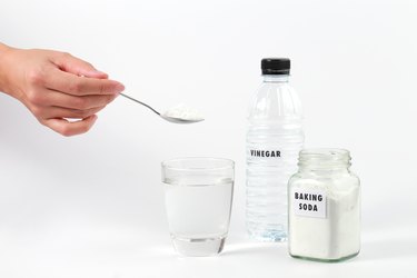 Close-Up Of Baking Soda And Vinegar On Table Against White Background