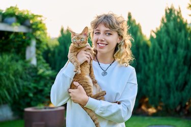 Outdoor portrait of teenage girl with pet cat in her arms