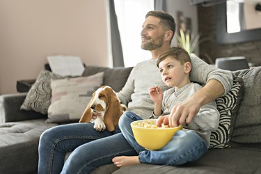 Father or Godfather with Basset dog having fun on the living room At Home watching movie with popcorn