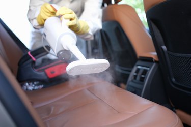 A man in protective clothing cleans the interior of a car from dirt