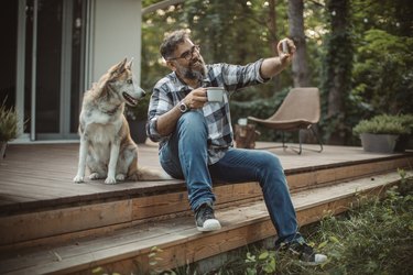 Man with his dog taking a photo on a porch in the woods