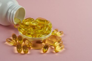 Omega 3 capsules on a pink background with a white bottle. Vitamins for a healthy heart.