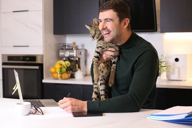 Man at computer desk holding cat