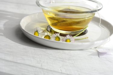 Aromatic medical chamomile tea whit chamomile/daisy flowers served on white wooden table