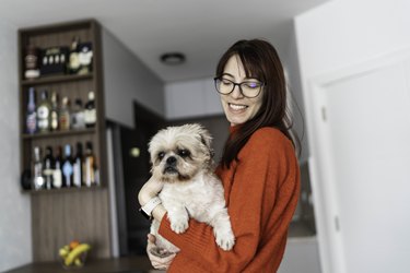 Young woman holding her dog and smiling.