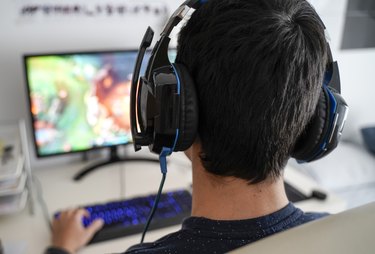 Boy with headphones playing a game on his computer