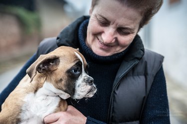 Senior Caucasian female holding and petting a dog