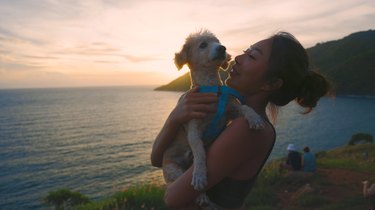 Asian woman hugging dog happy on the beach at travel and vacation