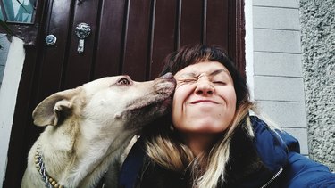 Close-Up Of Woman Sitting With Dog Against Closed Door