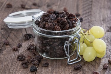 raisins in a jar next to grapes