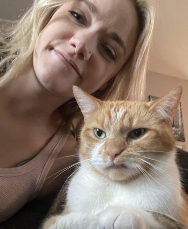 Cat does a snarl while sitting for a photo with their human.