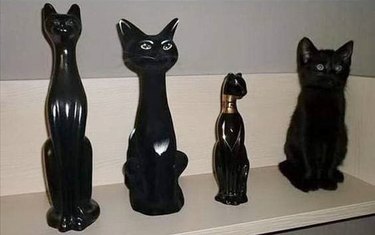 black cat next to figurine of Egyptian cat