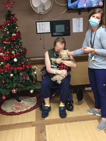 man in hospital holds his beloved dog.
