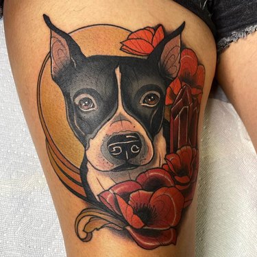 A tattoo of a dog's face surrounded by poppies.