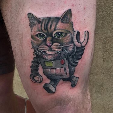 A tattoo of a robot with a realistic cat head.