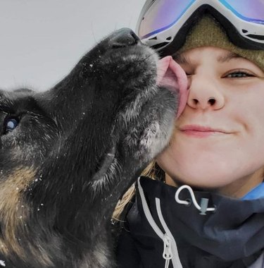 Dog kisses woman in snow goggles.