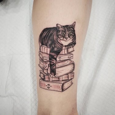 tattoo of cat on a stack of books