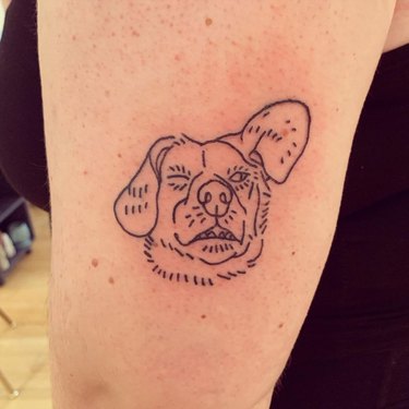 A minimalist tattoo of a dog's winking face.