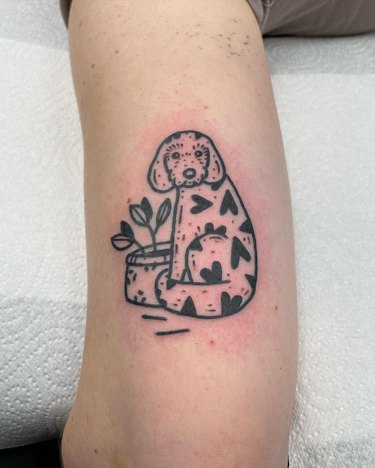 A tattoo of a dog with heart signs on their coat.