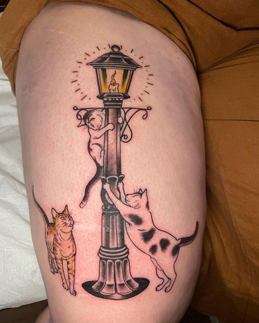A tattoo of cats climbing up a streetlight.