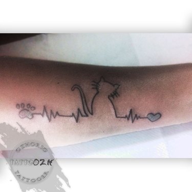 A tattoo of a cat silhouette and heartbeat.