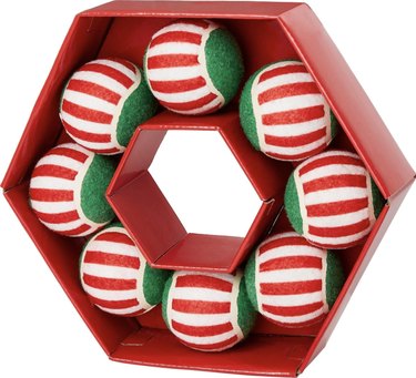 Wreath-shaped red box with 8 striped tennis balls inside that are red, white, and green.