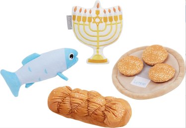 Hanukkah plush dog toys shaped like a fish, menorah, challah bread, and a plate of latkes.