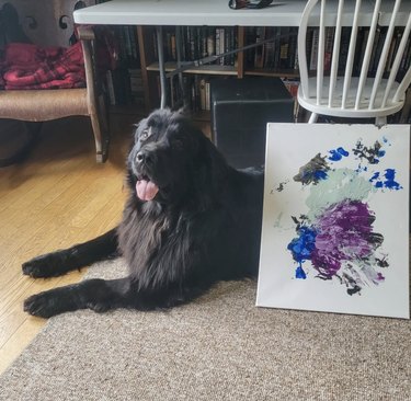 dog lying next to their painting.