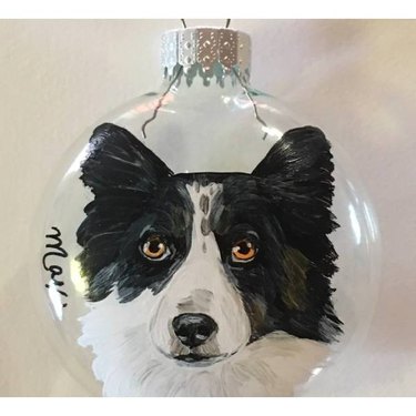 A clear ornament with a black and white dog painted on it