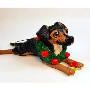 A figurine ornament of a black dog with a wretch around their neck