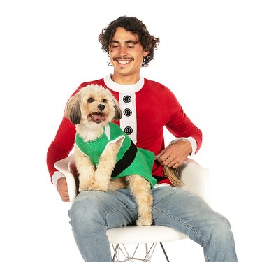 Man wearing a knit Santa sweater and small dog wearing knit green elf sweater.