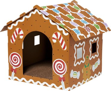 Gingerbread house-themed cardboard cat house with scratching surfaces and windows.