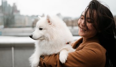 woman holds her happy and healthy dog on new years after making her pet resolutions