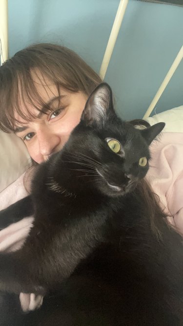 woman holding adopted black cat.