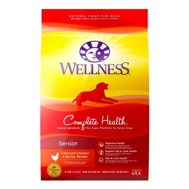 A yellow and red bag of Wellness Complete Health Senior Deboned Chicken & Barley Recipe Dry Dog Food