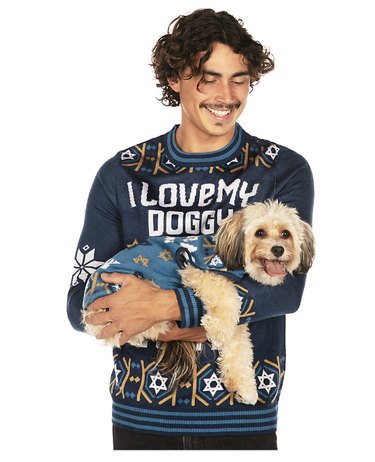 Man and dog in matching navy blue Hanukkah sweaters with the Star of David on them.