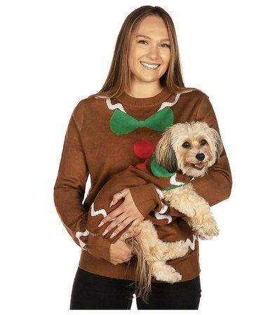 Woman and dog wearing matching gingerbread sweaters with icing, a green bow, and red buttons.