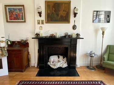 dog sleeping in decorative and non-operating fireplace.